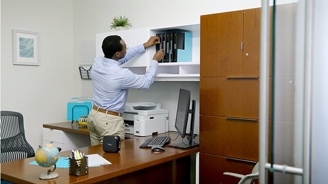 An African American actor puts labels on a bunch of office folders in this corporate video production