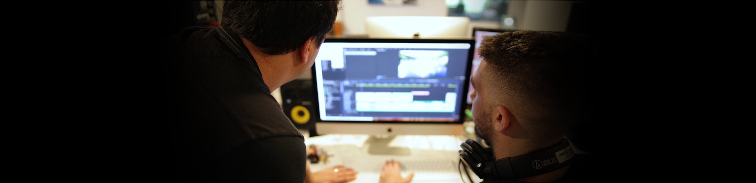 Two editors work on a mac computer for a commercial video edit