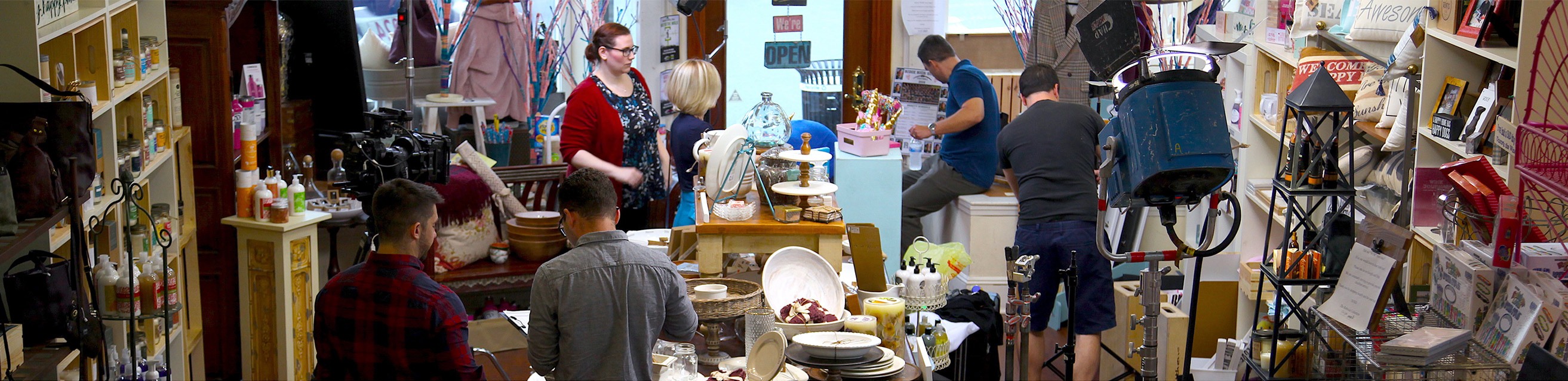 A wide panorama of a store busy with lighting and camera crew as well as actors prepping for a NJ commercial film shoot