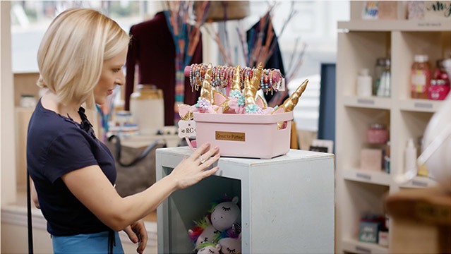 A female actress looks at items in a store while being filmed for commercial video marketing purposes