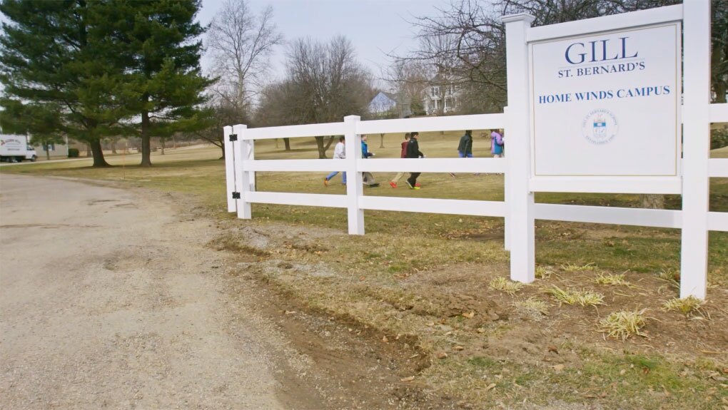 Students walk to school near a sign that says Gill St Bernards for an education video production