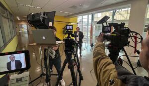 An on camera host talks with a live remote guest during a Media Company's film shoot