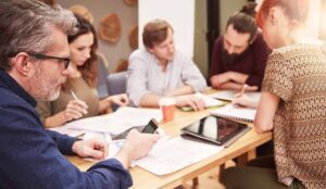 Office workers check their social media accounts while in a meeting