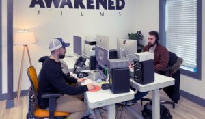 Two video marketers work on mac computers at Awakened Films