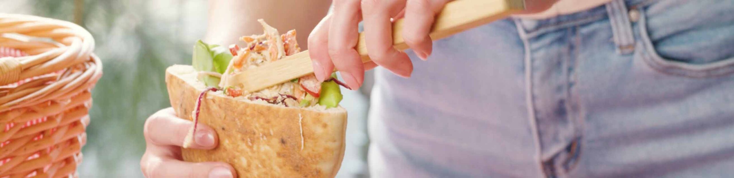 a woman making an angel bakeries pita sandwich