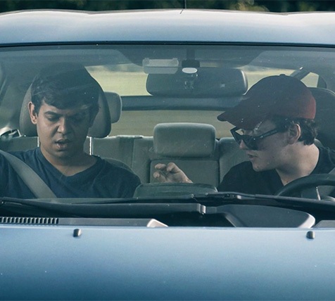 Two actors in a car are filmed for a movie