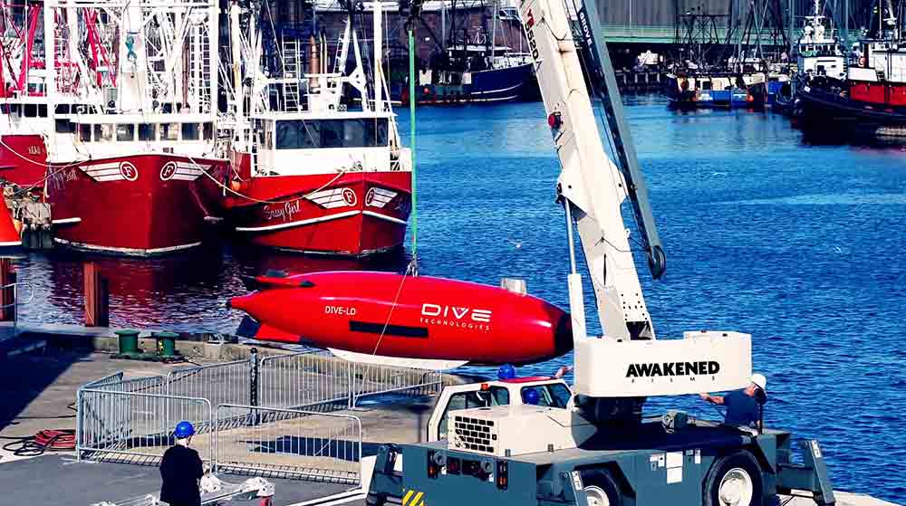 A crane lifts a small red submarine during a Corporate Video Production