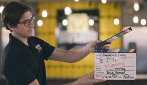 Crew from a media company hold up a film slate