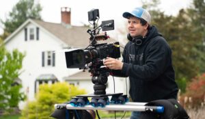 A Filmmaker at Awakened Films frames a shot with an anamorphic lens and dana dolly setup