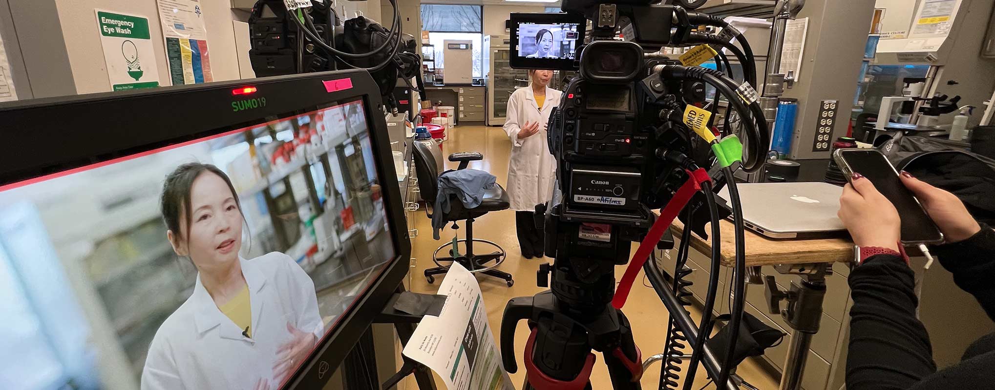 A corporate video production is taking place in a lab with cameras and a monitor
