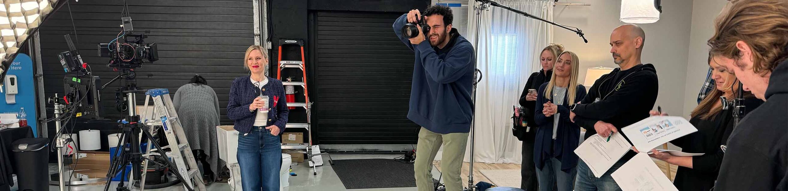 behind the scenes of a commercial video production, a photographer takes photos in a studio