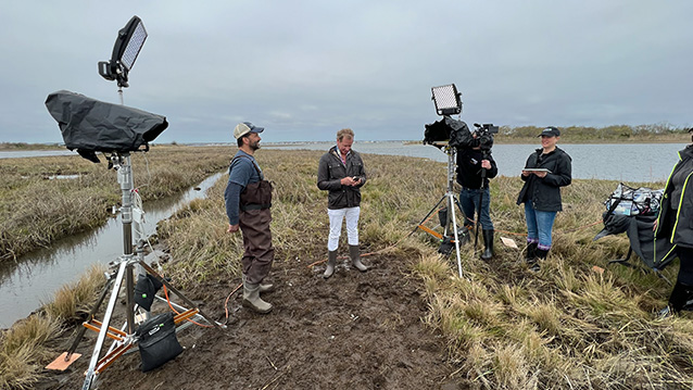 a nj video production crew sets up cameras and lights in the marsh for a nonprofit video