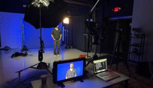 A crew member stands in front of lights, camera and teleprompter for a NJ Film Production in the Studios at Awakened Films.