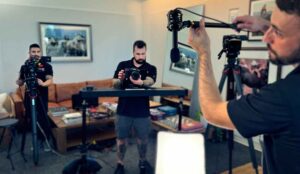 Three male crew members of Awakened Films adjust lights, cameras and audio during a video production filming