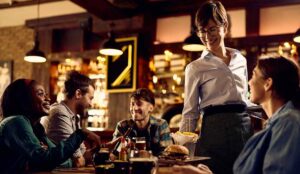 A restauranteur serves a table of happy diners in NJ