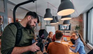 A cameraman films in an office for a corporate video production.