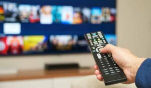 An actor holding a remote pointed at a TV is filmed for a commercial in NJ